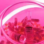 COVID Recovery - From above of glass bowl filled with pills and ampoules with vaccine for COVID 19 in pink bright neon light