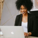 Webinar - Woman in Black Blazer Sitting by the Table While Using Macbook
