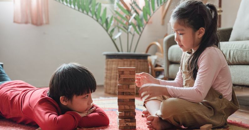Eco-friendly Build - Content Asian children building wooden tower on floor at home