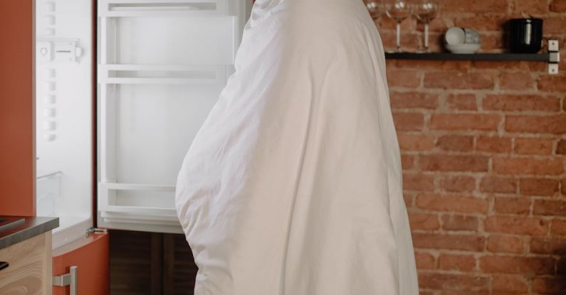Housing Shortage - Woman in White Hijab Standing Near White Top Mount Refrigerator